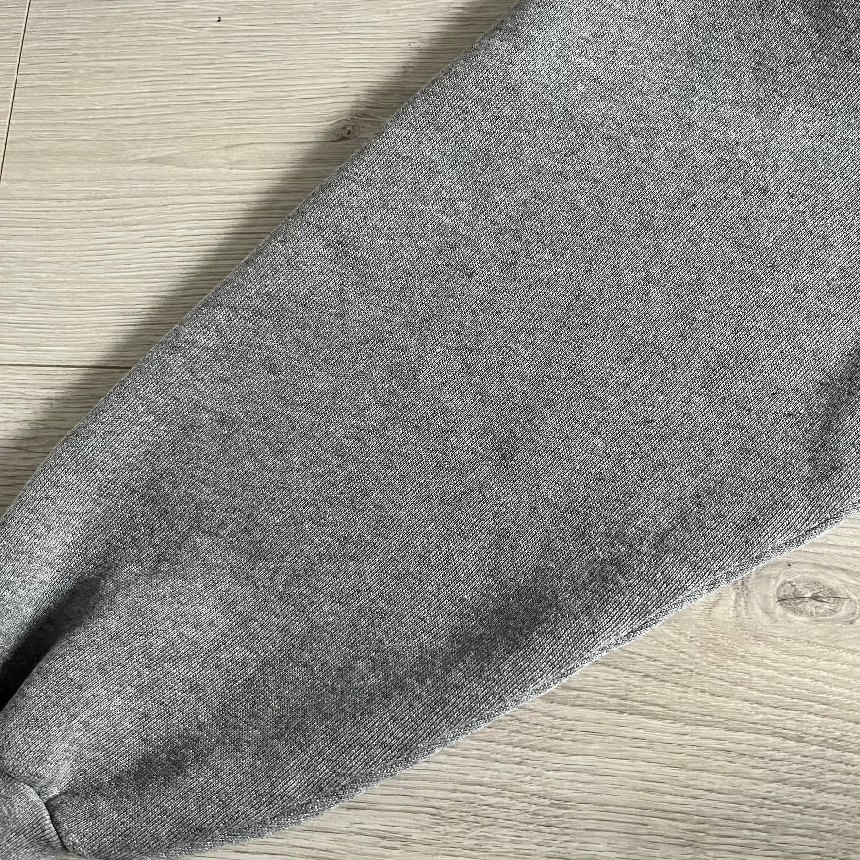 Balenciaga BB Crest Logo Hoodie in Heather Grey, crafted in Portugal from a heavyweight cotton-blend fleece (76% cotton, 24% polyester). The heather grey base features a dark navy BB emblem framed by laurel leaves and the Balenciaga logo text. Finished with dropped shoulders, ribbed edges, and a spacious front pocket, this oversized hoodie exemplifies elevated comfort and craftsmanship.