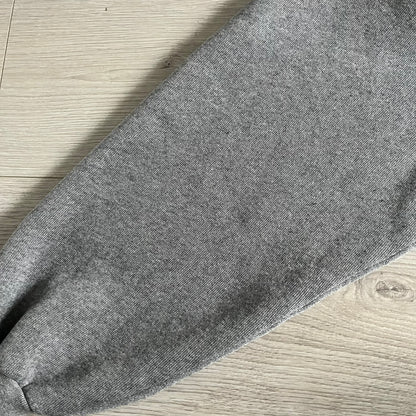 Balenciaga BB Crest Logo Hoodie in Heather Grey, crafted in Portugal from a heavyweight cotton-blend fleece (76% cotton, 24% polyester). The heather grey base features a dark navy BB emblem framed by laurel leaves and the Balenciaga logo text. Finished with dropped shoulders, ribbed edges, and a spacious front pocket, this oversized hoodie exemplifies elevated comfort and craftsmanship.