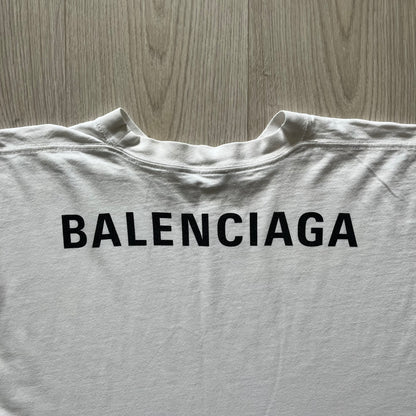 Balenciaga back logo tee from 2018, crafted in Portugal from soft white cotton. Designed with an oversized fit, it features a bold Balenciaga text logo across the upper back. Lower back part is a lot wider than front.