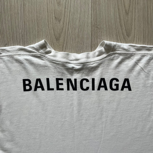 Balenciaga back logo tee from 2018, crafted in Portugal from soft white cotton. Designed with an oversized fit, it features a bold Balenciaga text logo across the upper back. Lower back part is a lot wider than front.
