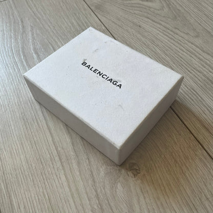 Balenciaga black leather card holder crafted in Italy from grained calfskin, featuring the updated Balenciaga logo in white inspired by public signage. Designed with four card slots and a central compartment, all fully lined in leather for durability. A sleek and practical accessory, it comes with a presentation box, reflecting Balenciaga’s modern luxury aesthetic under Demna Gvasalia’s creative direction.