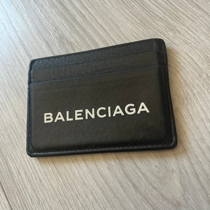  Balenciaga black leather card holder crafted in Italy from grained calfskin, featuring the updated Balenciaga logo in white inspired by public signage. Designed with four card slots and a central compartment, all fully lined in leather for durability. A sleek and practical accessory, it comes with a presentation box, reflecting Balenciaga’s modern luxury aesthetic under Demna Gvasalia’s creative direction.