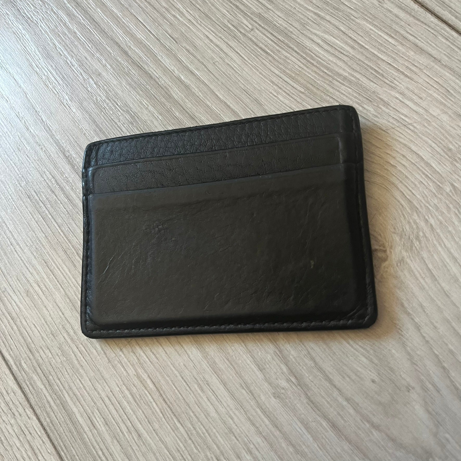  Balenciaga black leather card holder crafted in Italy from grained calfskin, featuring the updated Balenciaga logo in white inspired by public signage. Designed with four card slots and a central compartment, all fully lined in leather for durability. A sleek and practical accessory, it comes with a presentation box, reflecting Balenciaga’s modern luxury aesthetic under Demna Gvasalia’s creative direction.
