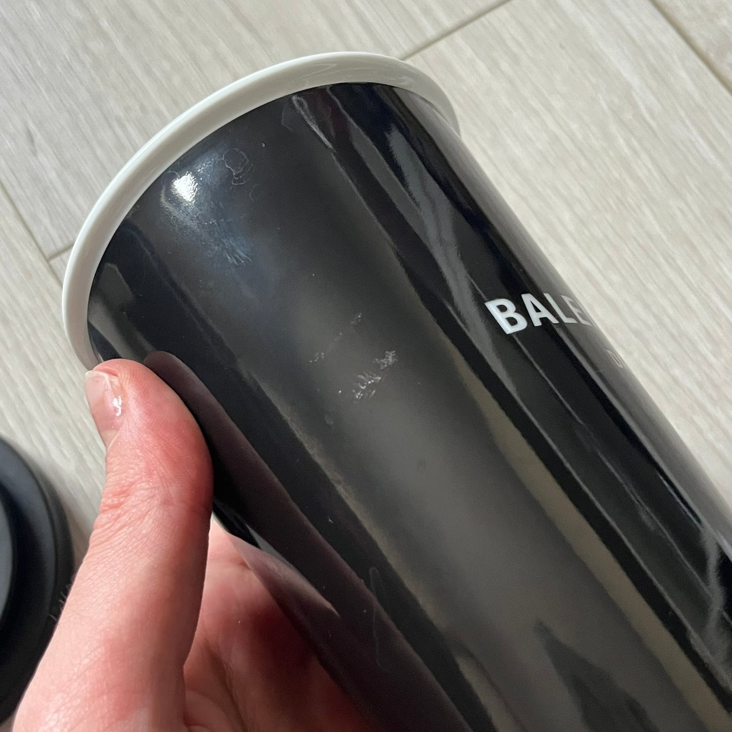 Balenciaga Dallas Black Coffee Cup crafted from glossy black porcelain with a white interior. Features a bold white Balenciaga logo with “Dallas” text underneath and a matching black rubber lid. A refined collectible showcasing everyday luxury.&nbsp;