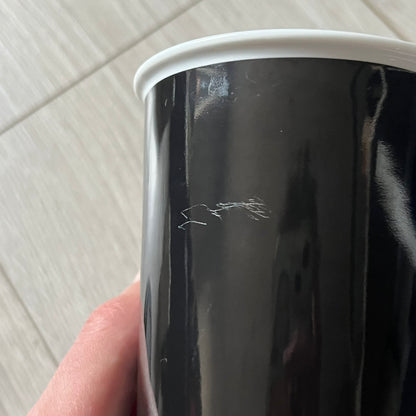 Balenciaga Dallas Black Coffee Cup crafted from glossy black porcelain with a white interior. Features a bold white Balenciaga logo with “Dallas” text underneath and a matching black rubber lid. A refined collectible showcasing everyday luxury.&nbsp;