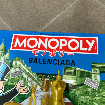 Balenciaga Monopoly 2025 VIP Gift Board Game features a custom Monopoly design made for Balenciaga. The game includes gold-tone fashion-themed playing pieces such as scissors, a thimble, thread spool, and mannequin. The board replaces standard properties with Balenciaga stores and locations, while the currency and cards feature Balenciaga branding and custom references including “Balenciaga Tax.”
