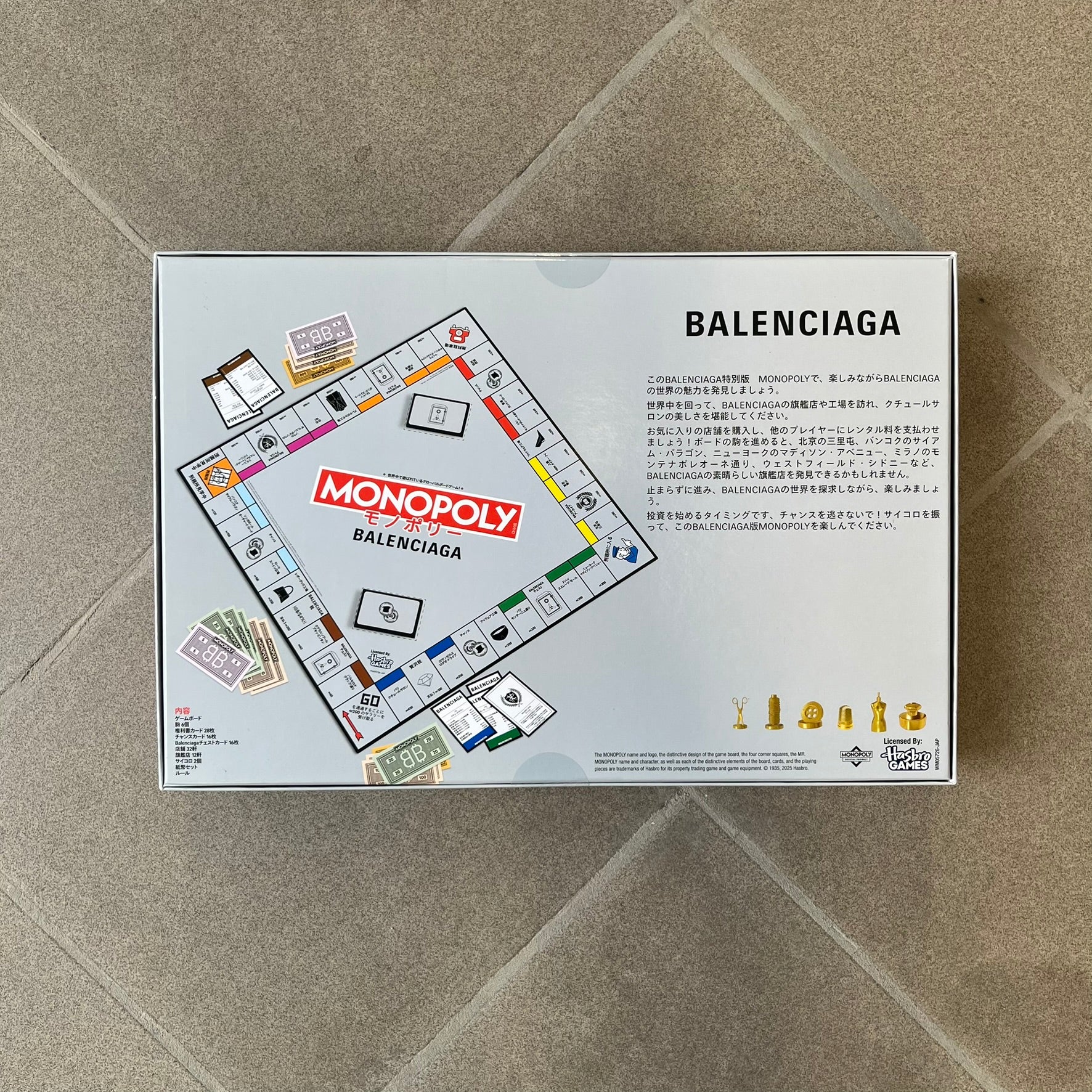 Balenciaga Monopoly 2025 VIP Gift Board Game features a custom Monopoly design made for Balenciaga. The game includes gold-tone fashion-themed playing pieces such as scissors, a thimble, thread spool, and mannequin. The board replaces standard properties with Balenciaga stores and locations, while the currency and cards feature Balenciaga branding and custom references including “Balenciaga Tax.”
