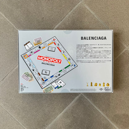 Balenciaga Monopoly 2025 VIP Gift Board Game features a custom Monopoly design made for Balenciaga. The game includes gold-tone fashion-themed playing pieces such as scissors, a thimble, thread spool, and mannequin. The board replaces standard properties with Balenciaga stores and locations, while the currency and cards feature Balenciaga branding and custom references including “Balenciaga Tax.”
