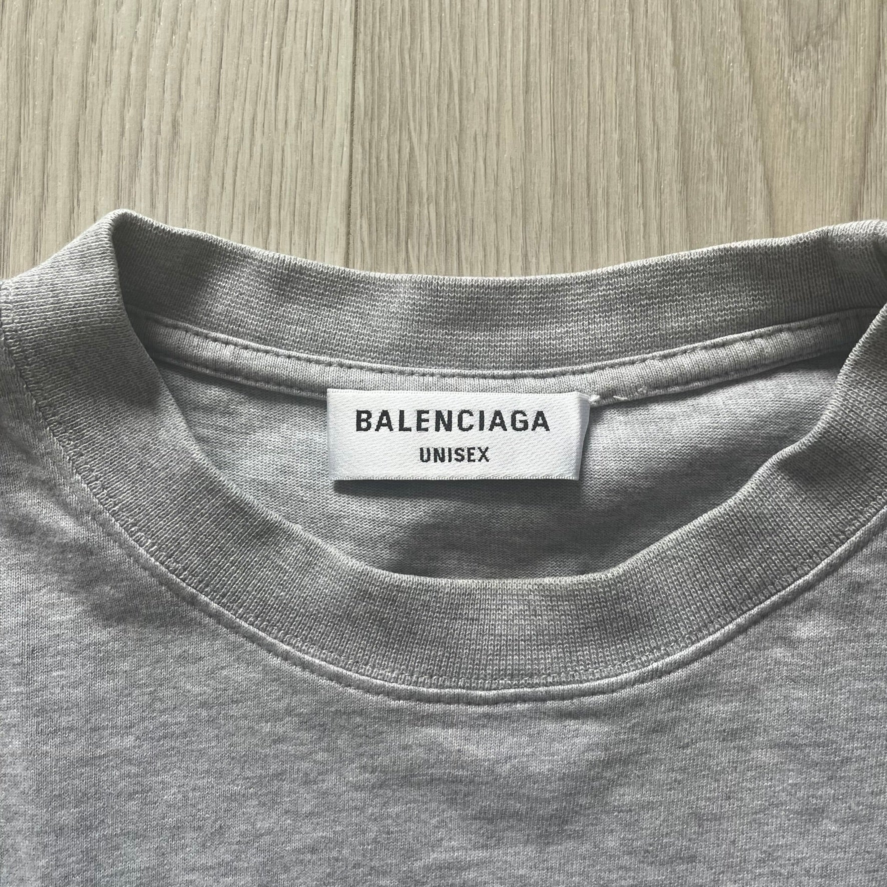 Gray t-shirt with Balenciaga label on a wooden surface