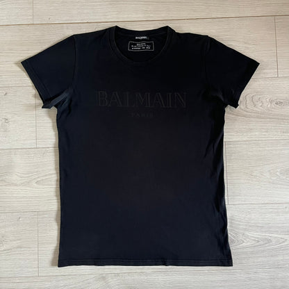 Balmain 2018 Black Tee featuring a discreet black Balmain Paris logo across the chest for a low-key, monochromatic effect. Constructed from soft 100% cotton and produced in Portugal, it embodies the brand’s modern, minimal direction.