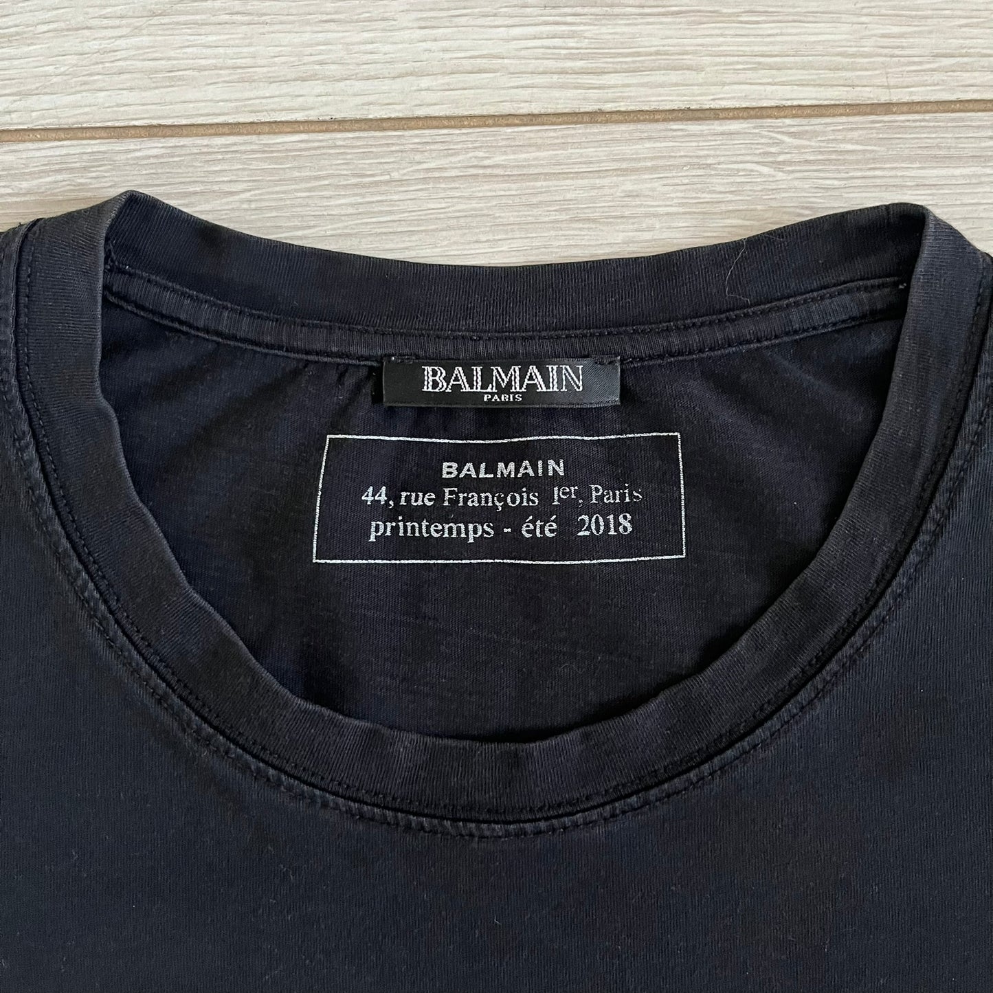 Balmain 2018 Black Tee featuring a discreet black Balmain Paris logo across the chest for a low-key, monochromatic effect. Constructed from soft 100% cotton and produced in Portugal, it embodies the brand’s modern, minimal direction.