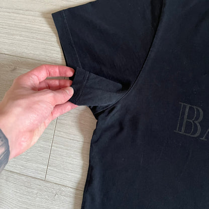 Balmain 2018 Black Tee featuring a discreet black Balmain Paris logo across the chest for a low-key, monochromatic effect. Constructed from soft 100% cotton and produced in Portugal, it embodies the brand’s modern, minimal direction.