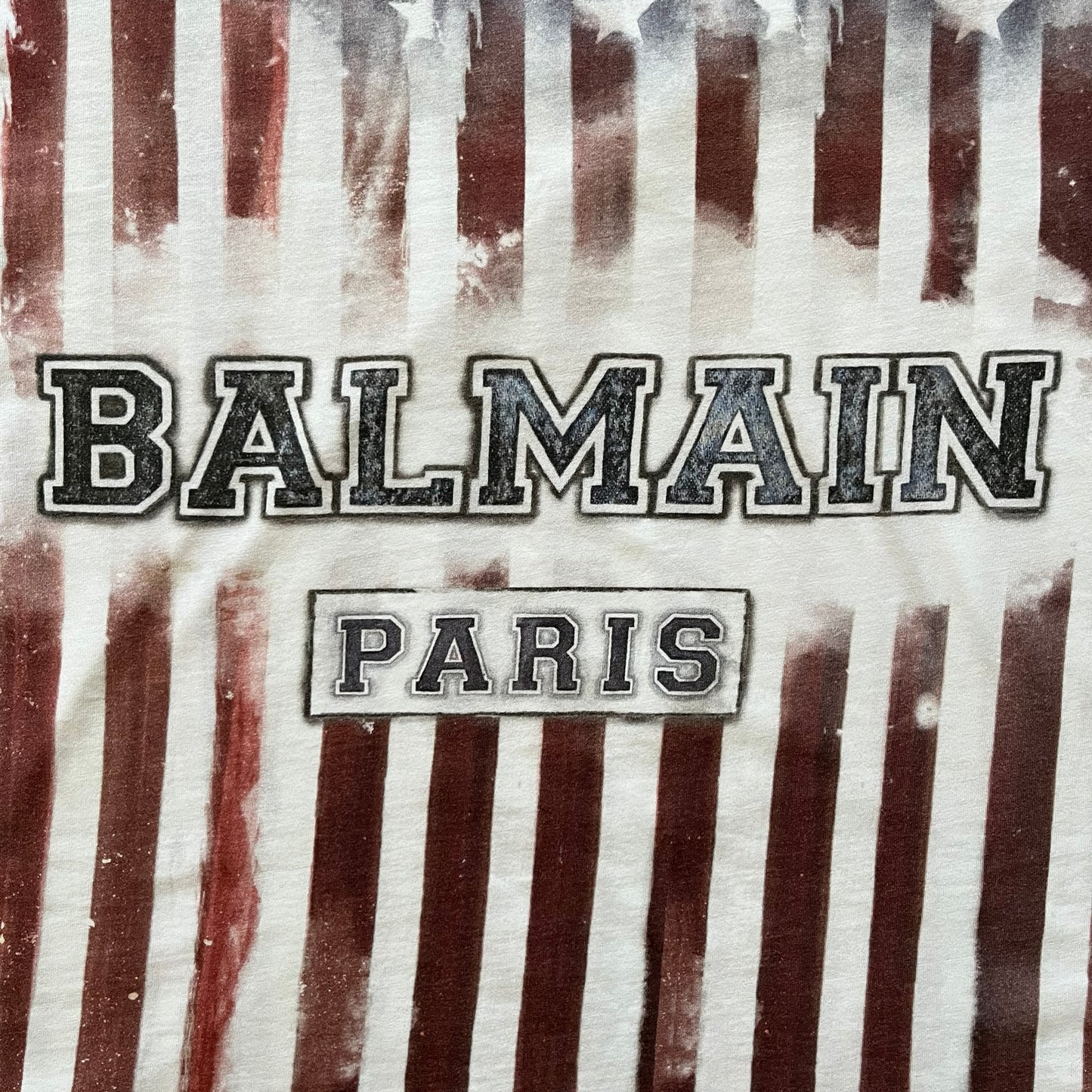 Balmain SS18 t-shirt in 100% cotton featuring a bold full-print USA flag on both sides. The front is accented with “Balmain Paris” text at the stomach, combining patriotic imagery with the brand’s signature luxury touch. A rare and powerful piece from the 2018 runway season.