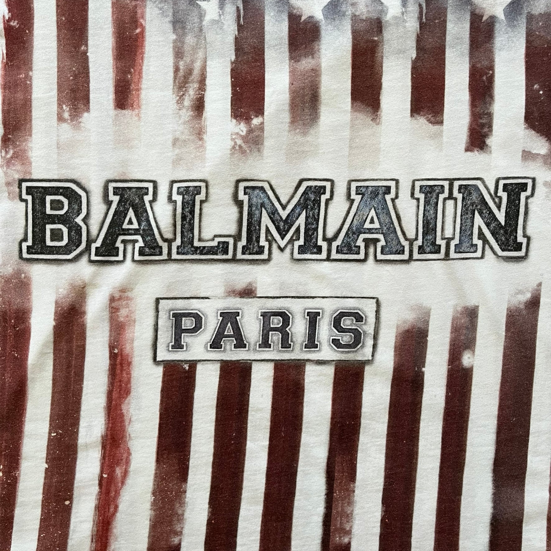 Balmain SS18 t-shirt in 100% cotton featuring a bold full-print USA flag on both sides. The front is accented with “Balmain Paris” text at the stomach, combining patriotic imagery with the brand’s signature luxury touch. A rare and powerful piece from the 2018 runway season.