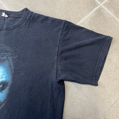 Batman The Dark Knight 2008 Joker Promo Tee features a black construction made on an Anvil blank, with Heath Ledger as the Joker holding a Batman playing card printed on the front. The upper back has The Dark Knight logo with small DC Comics 2008 licensing text underneath.
