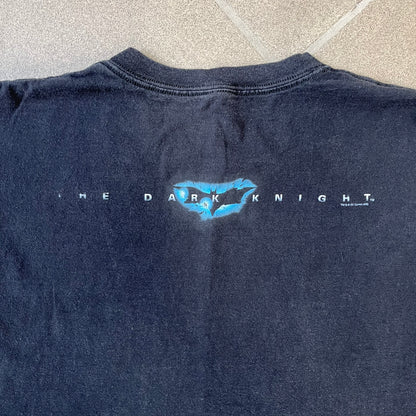 Batman The Dark Knight 2008 Joker Promo Tee features a black construction made on an Anvil blank, with Heath Ledger as the Joker holding a Batman playing card printed on the front. The upper back has The Dark Knight logo with small DC Comics 2008 licensing text underneath.
