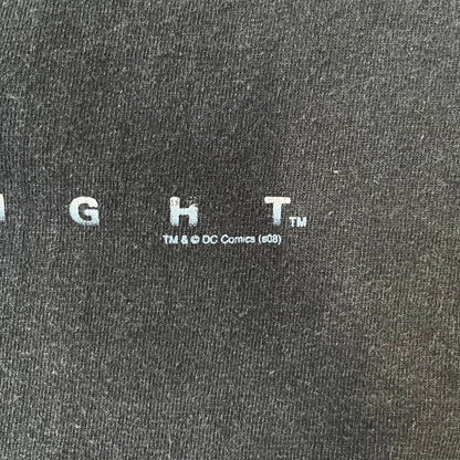 Batman The Dark Knight 2008 Joker Promo Tee features a black construction made on an Anvil blank, with Heath Ledger as the Joker holding a Batman playing card printed on the front. The upper back has The Dark Knight logo with small DC Comics 2008 licensing text underneath.
