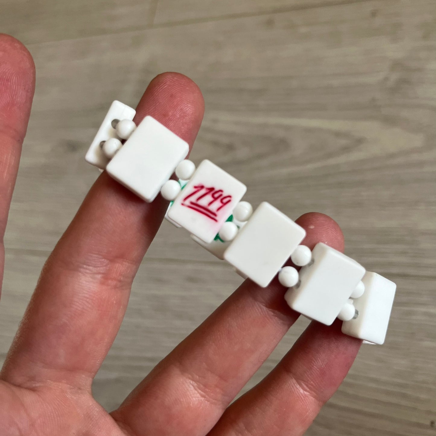 Bazo 1199 “420” Bracelet is a white silicone bead bracelet featuring glitter cannabis leaf graphics across the beads and a “420” emoji graphic on one bead. The interior includes a glitter red 1199 logo. It comes in the original plastic foil packaging.&nbsp;