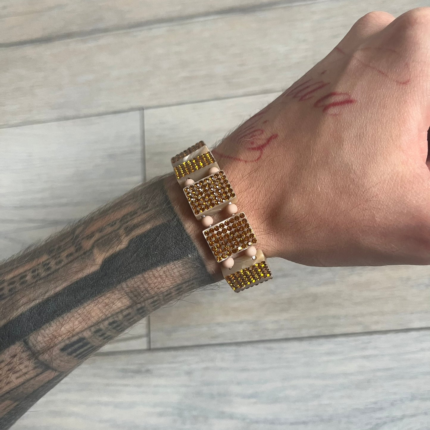 Bazo 1199 x 63KLUF Rhinestone Bracelet is a wooden bead bracelet from the 1199 and 63KLUF collaboration. The outer side is covered with gold and orange-toned rhinestones, while the inner side has a pearly beige finish. The interior is marked with black 1199 and 63KLUF logos.
