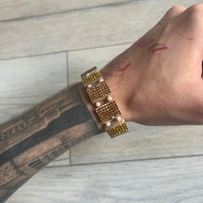 Bazo 1199 x 63KLUF Rhinestone Bracelet is a wooden bead bracelet from the 1199 and 63KLUF collaboration. The outer side is covered with gold and orange-toned rhinestones, while the inner side has a pearly beige finish. The interior is marked with black 1199 and 63KLUF logos.