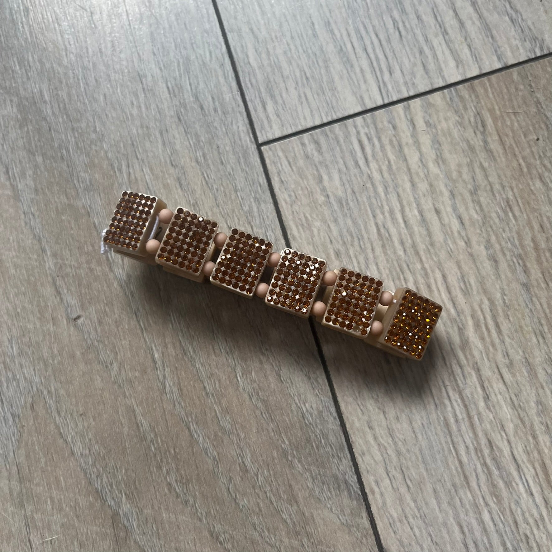 Bazo 1199 x 63KLUF Rhinestone Bracelet is a wooden bead bracelet from the 1199 and 63KLUF collaboration. The outer side is covered with gold and orange-toned rhinestones, while the inner side has a pearly beige finish. The interior is marked with black 1199 and 63KLUF logos.