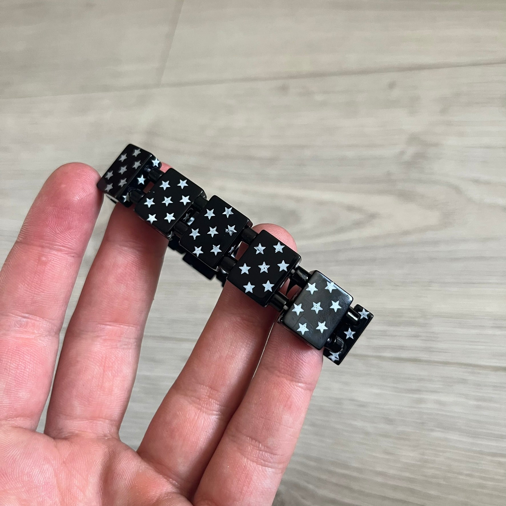 Bazo 1199 “Black on White” Stars Bracelet is a acetate bead bracelet featuring black beads with white star graphics printed on the tops and sides. One bead is marked with a red 1199 logo on the inside. It comes with the original foil packaging.
