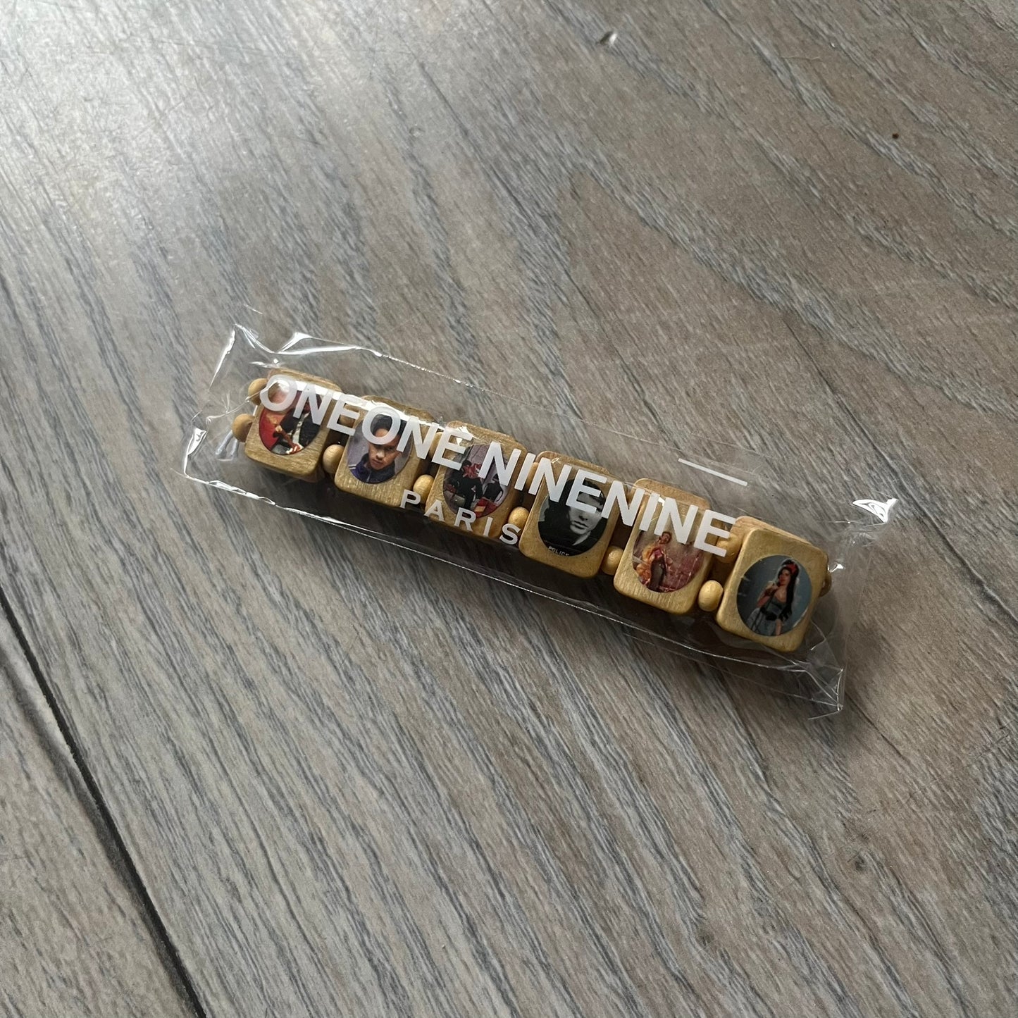 Beige “Forever 27 Club” bracelet by Bazo 1199, showcasing painted wooden beads and engraved portraits of legendary artists from the infamous 27 Club like Kurt Cobain, Basquiat, and Fredo Santana. Signed “forever 27 club” and “1199” on the inside.