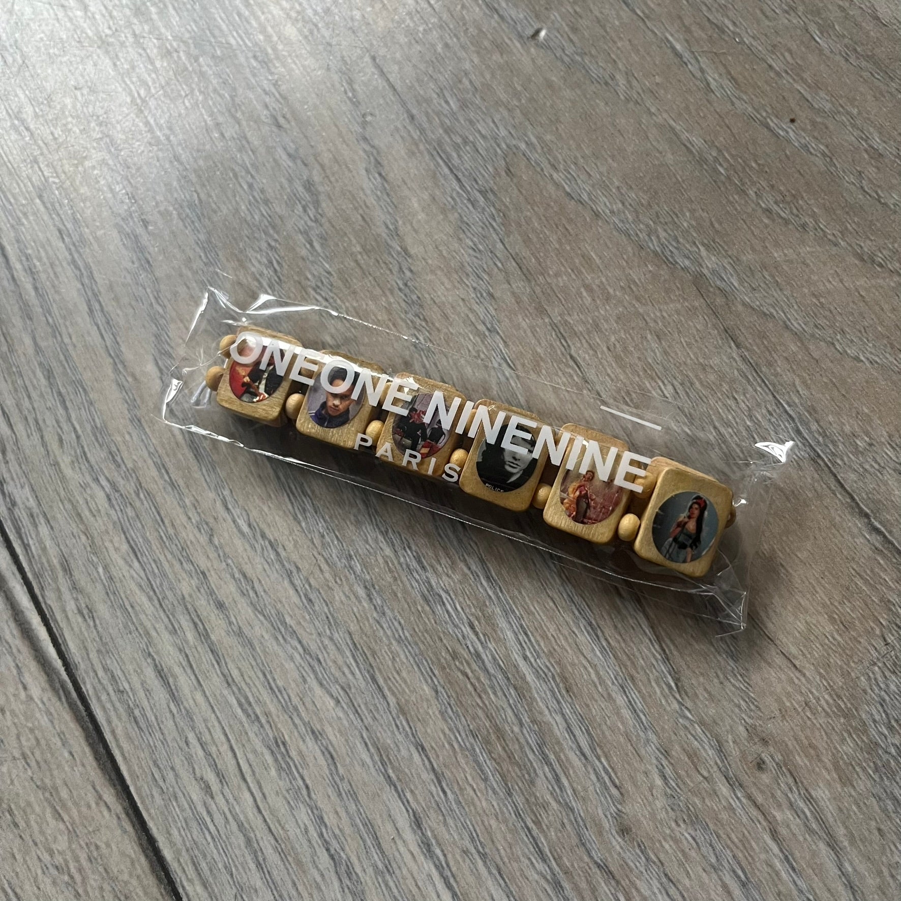 Beige “Forever 27 Club” bracelet by Bazo 1199, showcasing painted wooden beads and engraved portraits of legendary artists from the infamous 27 Club like Kurt Cobain, Basquiat, and Fredo Santana. Signed “forever 27 club” and “1199” on the inside.