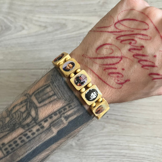 Beige “Forever 27 Club” bracelet by Bazo 1199, showcasing painted wooden beads and engraved portraits of legendary artists from the infamous 27 Club like Kurt Cobain, Basquiat, and Fredo Santana. Signed “forever 27 club” and “1199” on the inside.