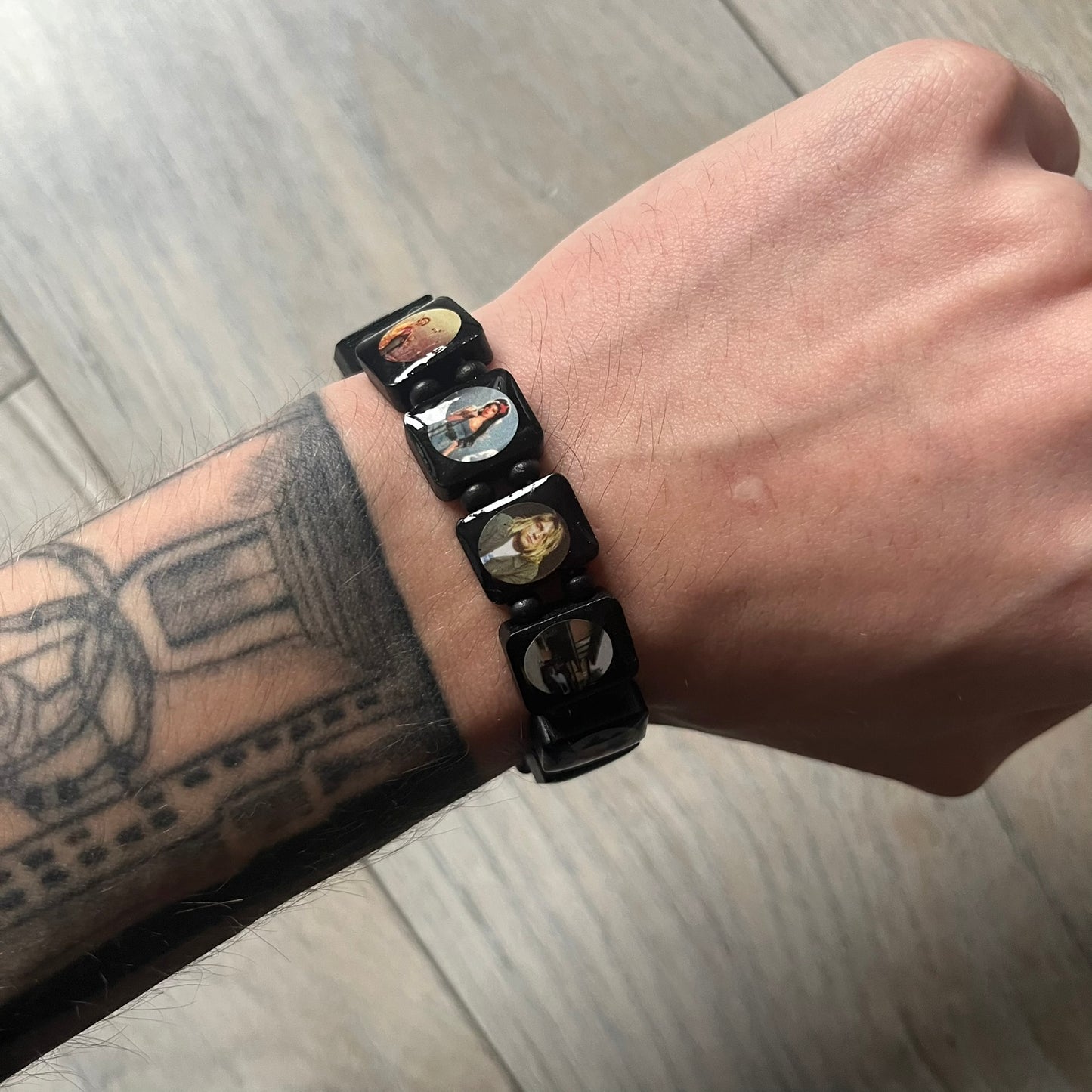 Black “Forever 27 Club” bracelet by Bazo 1199, showcasing painted wooden beads and engraved portraits of legendary artists from the infamous 27 Club like Kurt Cobain, Basquiat, and Fredo Santana. Signed “forever 27 club” and “1199” on the inside.
