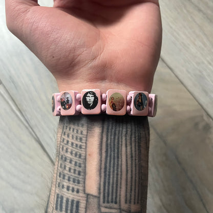 Blushing Bride “Forever 27 Club” bracelet by Bazo 1199, showcasing painted wooden beads and engraved portraits of legendary artists from the infamous 27 Club like Kurt Cobain, Basquiat, and Fredo Santana. Signed “forever 27 club” and “1199” on the inside.