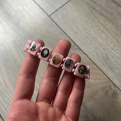 Blushing Bride “Forever 27 Club” bracelet by Bazo 1199, showcasing painted wooden beads and engraved portraits of legendary artists from the infamous 27 Club like Kurt Cobain, Basquiat, and Fredo Santana. Signed “forever 27 club” and “1199” on the inside.