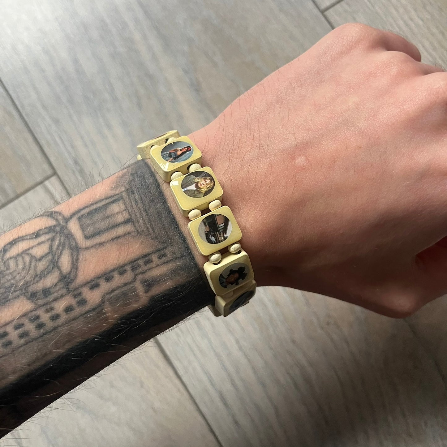Pastel Yellow “Forever 27 Club” bracelet by Bazo 1199, showcasing painted wooden beads and engraved portraits of legendary artists from the infamous 27 Club like Kurt Cobain, Basquiat, and Fredo Santana. Signed “forever 27 club” and “1199” on the inside.