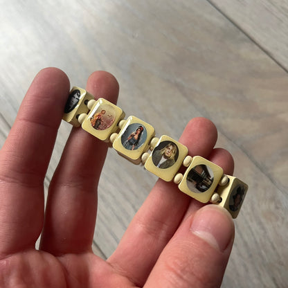 Pastel Yellow “Forever 27 Club” bracelet by Bazo 1199, showcasing painted wooden beads and engraved portraits of legendary artists from the infamous 27 Club like Kurt Cobain, Basquiat, and Fredo Santana. Signed “forever 27 club” and “1199” on the inside.