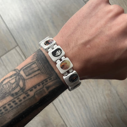 White “Forever 27 Club” bracelet by Bazo 1199, showcasing painted wooden beads and engraved portraits of legendary artists from the infamous 27 Club like Kurt Cobain, Basquiat, and Fredo Santana. Signed “forever 27 club” and “1199” on the inside.