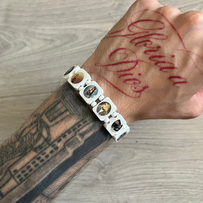 White “Forever 27 Club” bracelet by Bazo 1199, showcasing painted wooden beads and engraved portraits of legendary artists from the infamous 27 Club like Kurt Cobain, Basquiat, and Fredo Santana. Signed “forever 27 club” and “1199” on the inside.