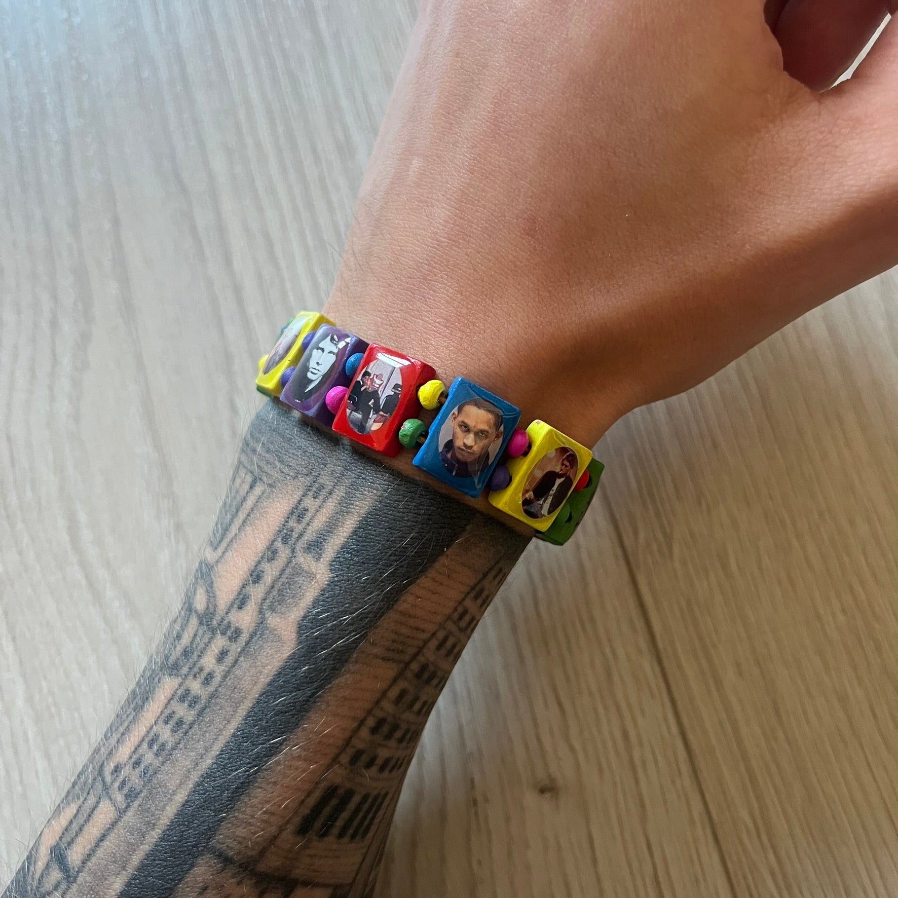 Multicolor “Forever 27” bracelet by Bazo 1199, showcasing painted wooden beads and engraved portraits of legendary artists from the infamous 27 Club like Kurt Cobain, Basquiat, and Fredo Santana. Signed “forever 27” and “1199” on the inside, this piece is a striking nod to music and art history. Limited and highly sought-after, it captures both style and cultural significance.