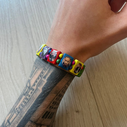 Multicolor “Forever 27” bracelet by Bazo 1199, showcasing painted wooden beads and engraved portraits of legendary artists from the infamous 27 Club like Kurt Cobain, Basquiat, and Fredo Santana. Signed “forever 27” and “1199” on the inside, this piece is a striking nod to music and art history. Limited and highly sought-after, it captures both style and cultural significance.
