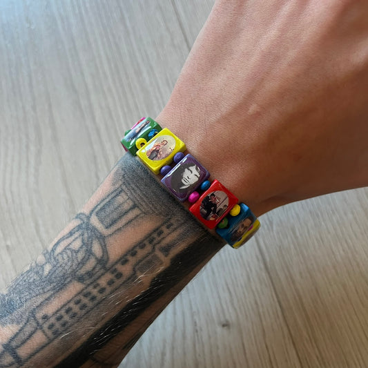Multicolor “Forever 27” bracelet by Bazo 1199, showcasing painted wooden beads and engraved portraits of legendary artists from the infamous 27 Club like Kurt Cobain, Basquiat, and Fredo Santana. Signed “forever 27” and “1199” on the inside, this piece is a striking nod to music and art history. Limited and highly sought-after, it captures both style and cultural significance.