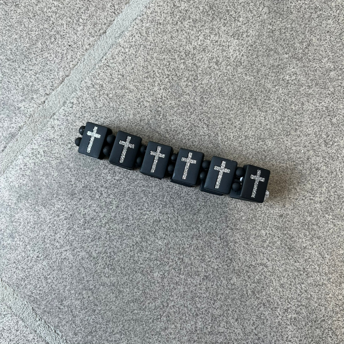 Bazo 1199 “God’s Lonely Kids” Bracelet is a black silicone bead bracelet featuring crystal cross details on the outside of each bead. The interior is engraved with the 1199 logo and “God’s Lonely Kids” text.