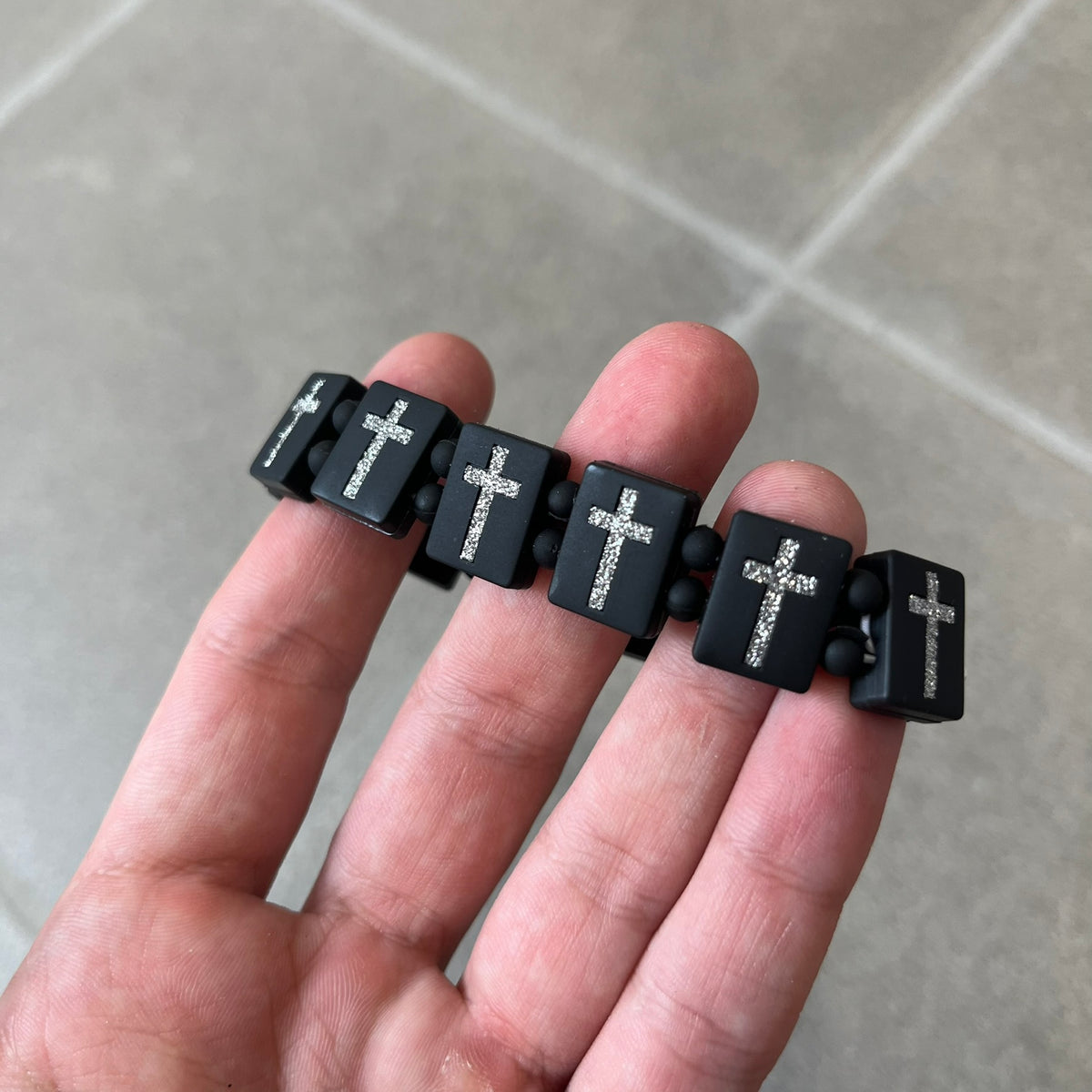 Bazo 1199 “God’s Lonely Kids” Bracelet is a black silicone bead bracelet featuring crystal cross details on the outside of each bead. The interior is engraved with the 1199 logo and “God’s Lonely Kids” text.