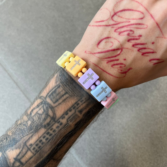 Bazo 1199 “God’s Lonely Kids” Bracelet is a multicolor silicone bead bracelet featuring crystal cross details on the outside of each bead. The interior is engraved with the 1199 logo and “God’s Lonely Kids” text.&nbsp;