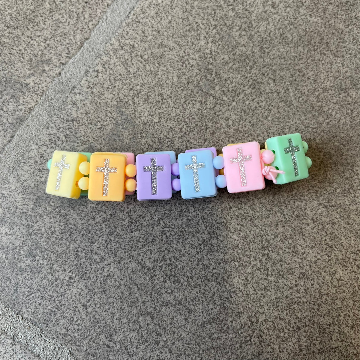 Bazo 1199 “God’s Lonely Kids” Bracelet is a multicolor silicone bead bracelet featuring crystal cross details on the outside of each bead. The interior is engraved with the 1199 logo and “God’s Lonely Kids” text.&nbsp;