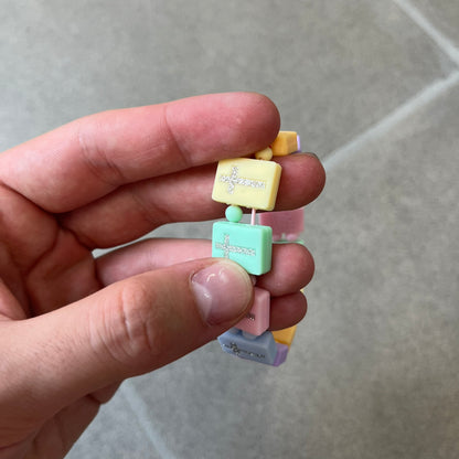 Bazo 1199 “God’s Lonely Kids” Bracelet is a multicolor silicone bead bracelet featuring crystal cross details on the outside of each bead. The interior is engraved with the 1199 logo and “God’s Lonely Kids” text.&nbsp;