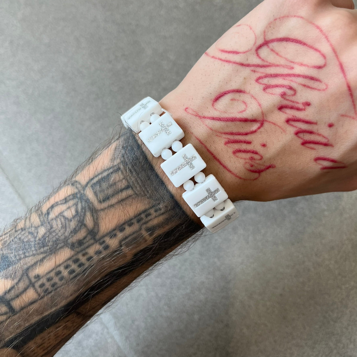 Bazo 1199 “God’s Lonely Kids” Bracelet is a white silicone bead bracelet featuring crystal cross details on the outside of each bead. The interior is engraved with the 1199 logo and “God’s Lonely Kids” text.