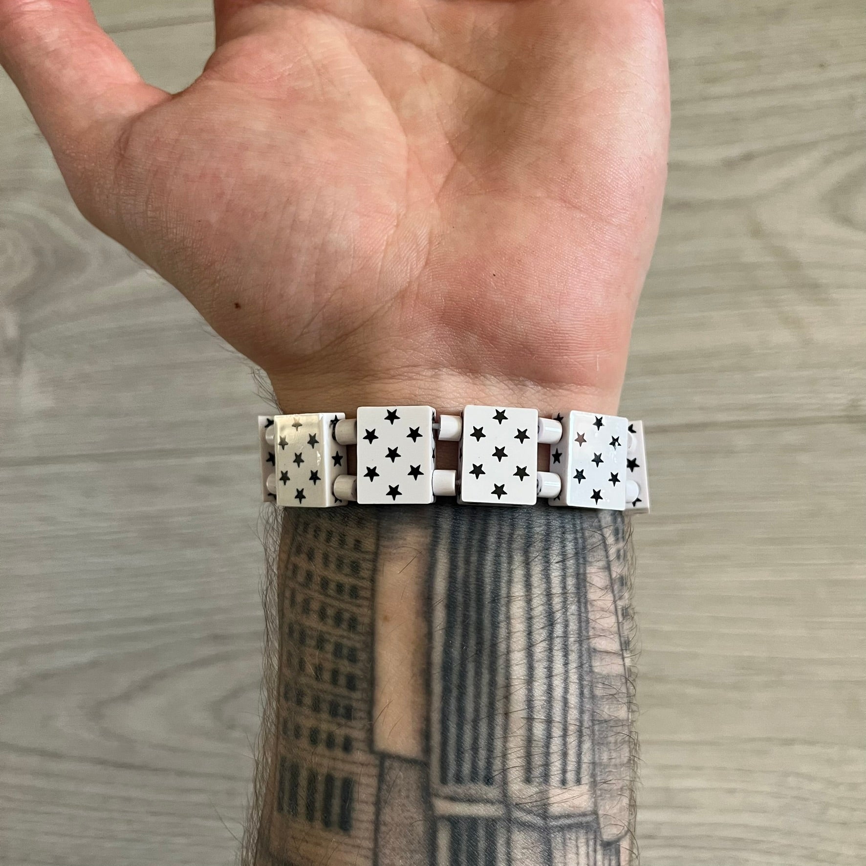 Bazo 1199 “White on Black” Stars Bracelet is a acetate bead bracelet featuring white beads with black star graphics printed on the tops and sides. One bead is marked with a red 1199 logo on the inside. It comes with the original foil packaging.
