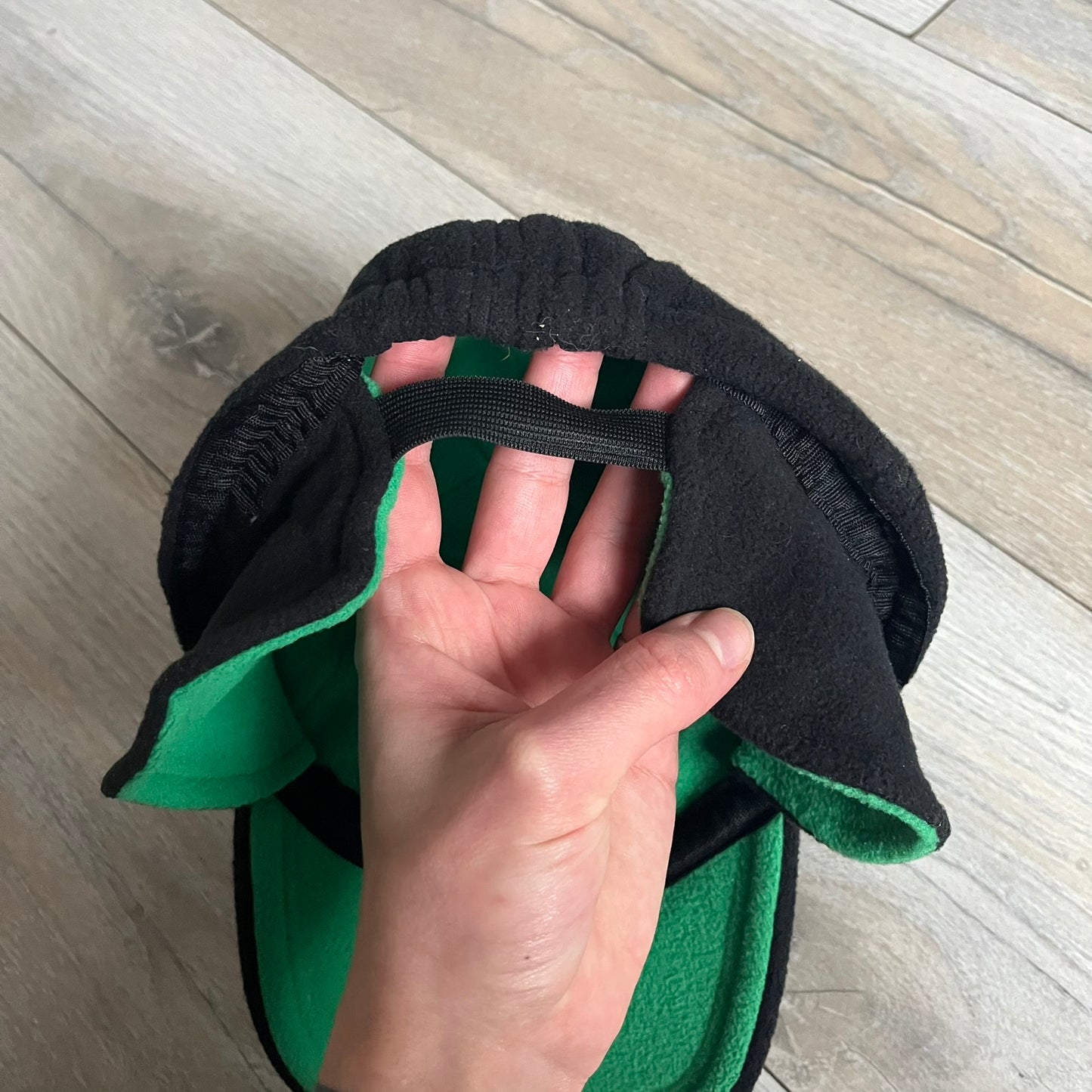 Ben 10 Alien Force Earflap 2011 Hat is a black polyester kids-size hat with green interior lining and earflaps on both sides. The front features embroidered Ben 10 character graphics with “Ben 10 Alien Force” text. Finished with an official 2011 Cartoon Network tag and a soft overall construction.