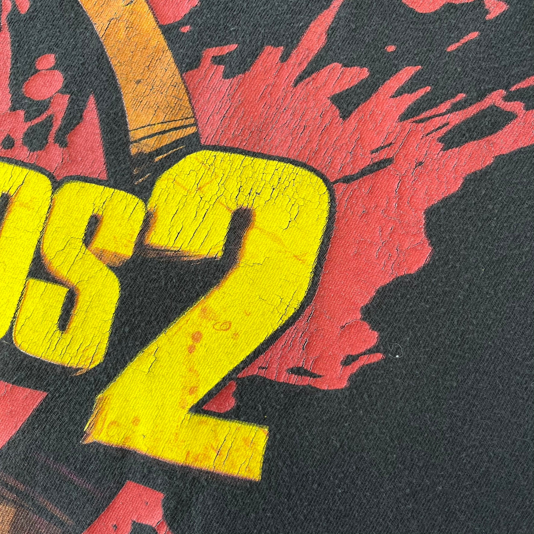 Borderlands 2 Promo 2010's Tee features a black boxy construction with a thick yellow and red Borderlands 2 logo printed on the front. A blood-splatter graphic appears behind the logo, and the shirt is made from 100% cotton.
