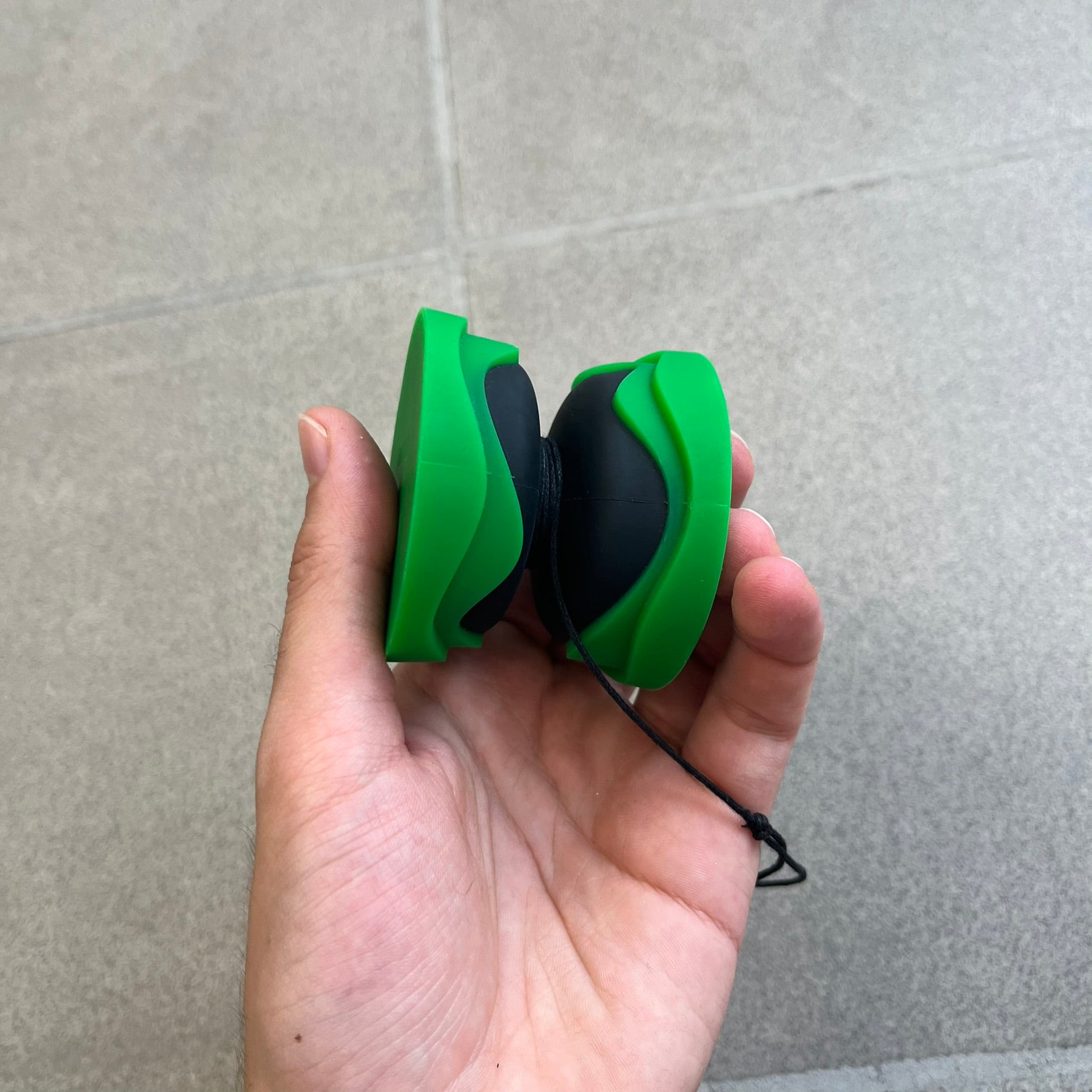 Bottega Veneta Green Rubber Yo-Yo is a collectible accessory crafted from green and black silicone. It features green outer halves with a black center section, a black string, and an engraved Bottega Veneta logo on one side. The yo-yo comes complete with its original box and paper bag.
