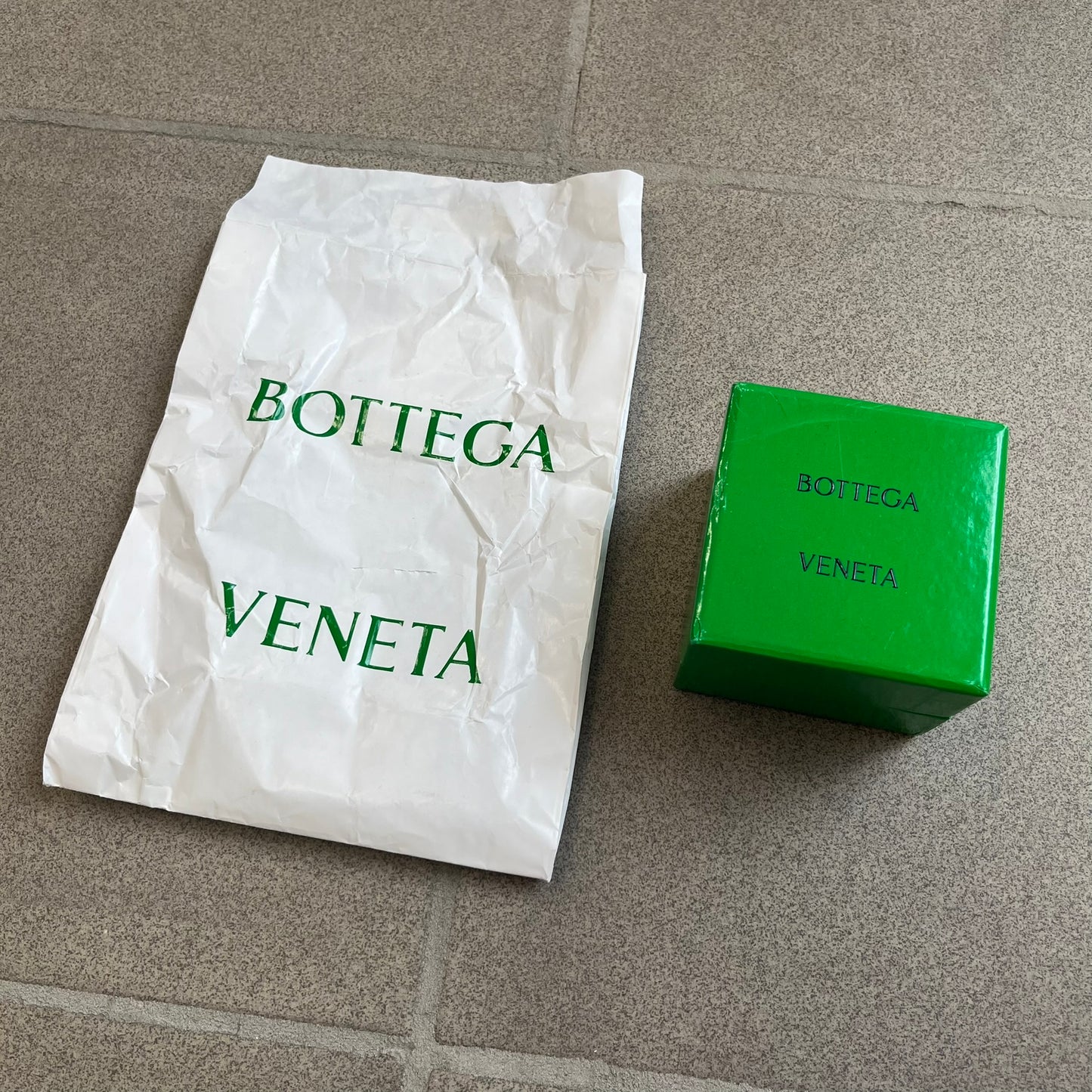Bottega Veneta Green Rubber Yo-Yo is a collectible accessory crafted from green and black silicone. It features green outer halves with a black center section, a black string, and an engraved Bottega Veneta logo on one side. The yo-yo comes complete with its original box and paper bag.
